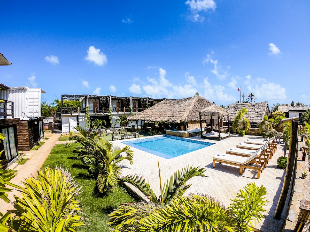 Luxurious tropical resort featuring a swimming pool and lush surroundings under a clear blue sky.