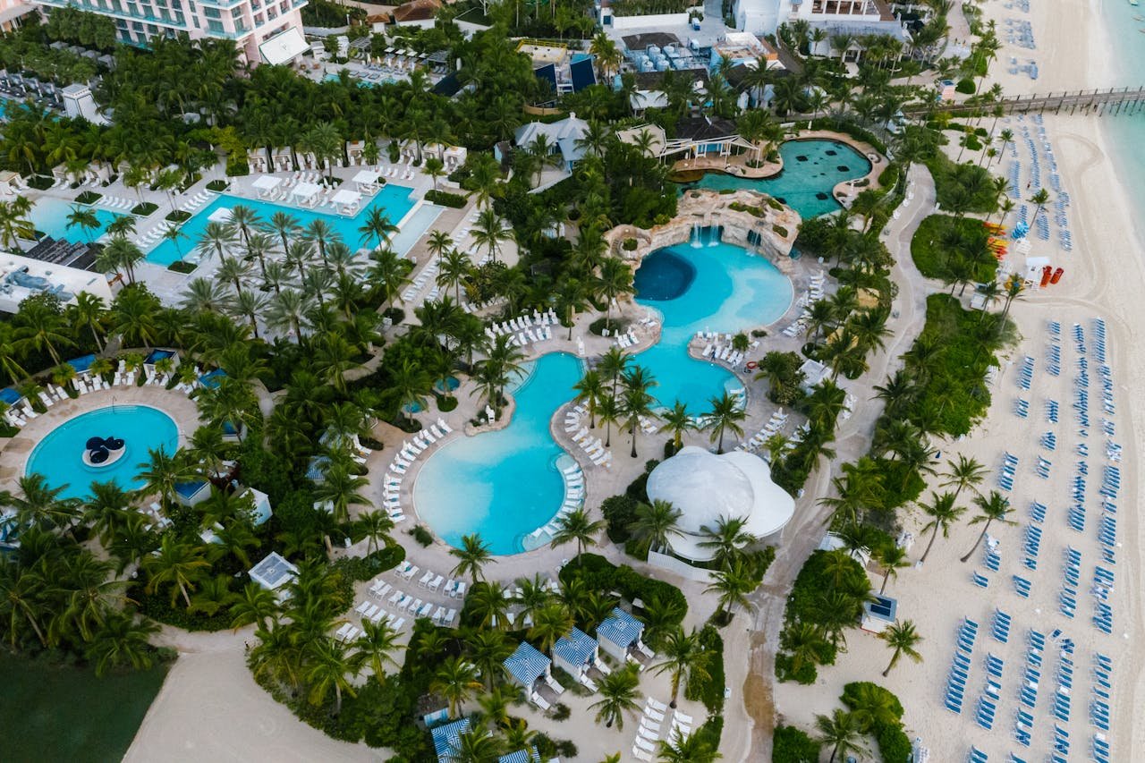 A stunning aerial view of a luxurious beachfront resort with swimming pools and palm trees.